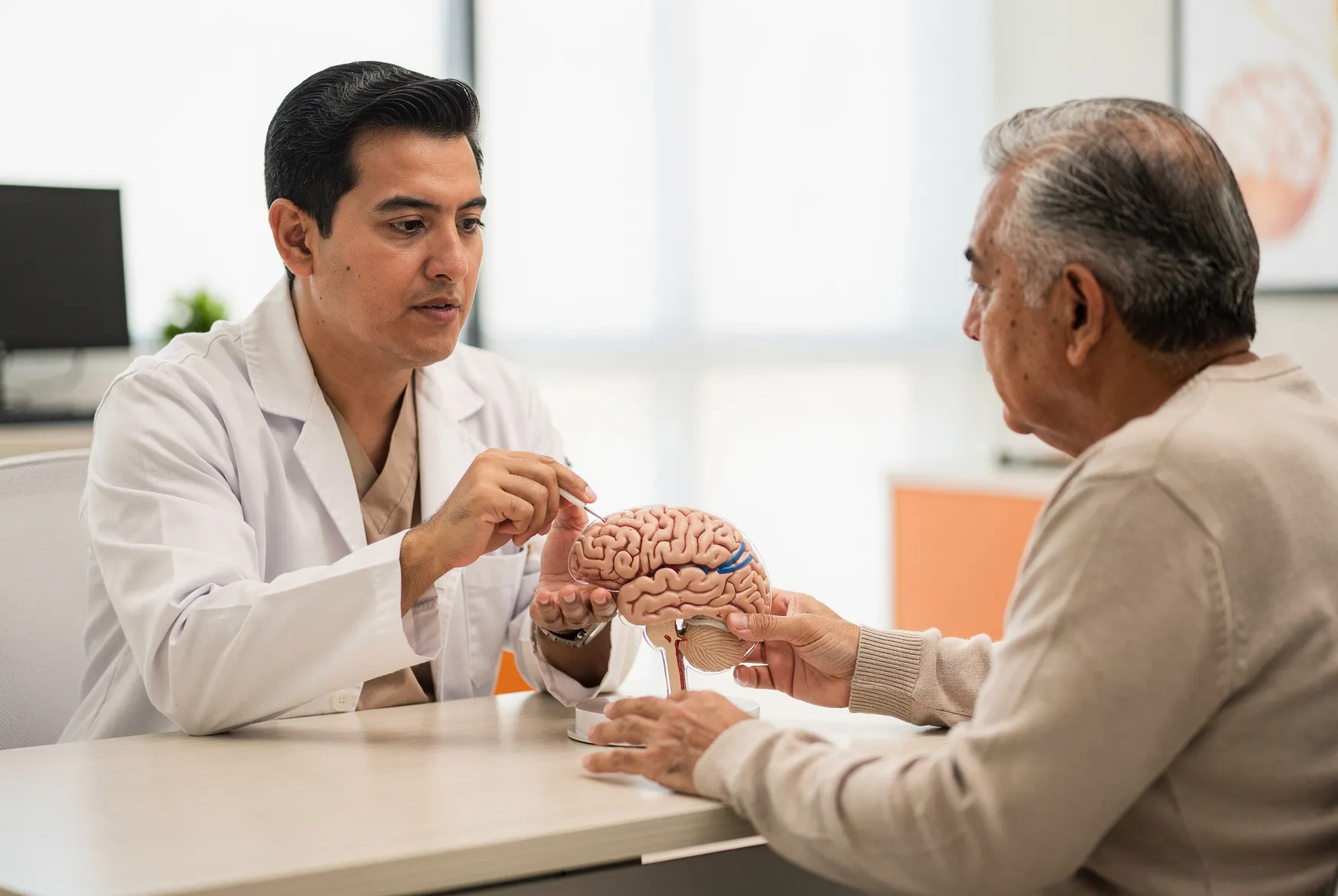 Neurólogo explicando el Parkinson con un modelo de cerebro a un paciente en Neurocenter